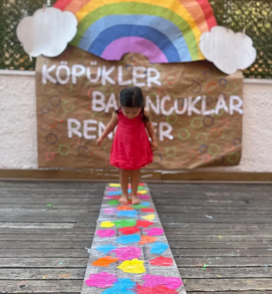 Üç yaş grubu çocuk renkli duyusal parkurda yürüyor — köpükler ve renkler etkinliği 